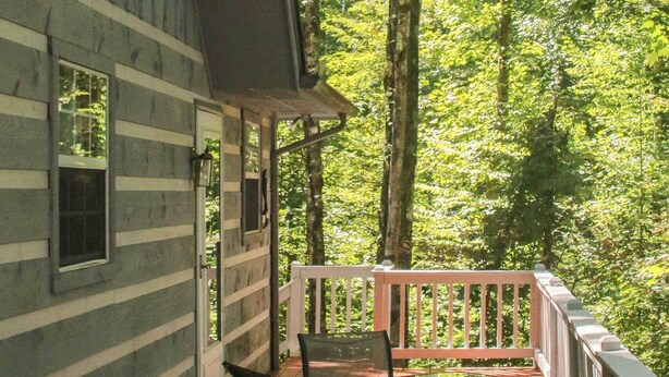 Een houten hut met een terras, een tafel en stoelen.