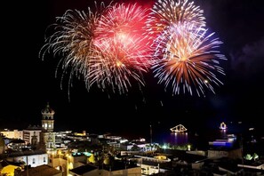 Une vue nocturne d’une ville, avec des feux d’artifice, des bâtiments historiques et un front de mer.