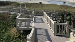 A wooden boardwalk leading to a beach with a clear sky.