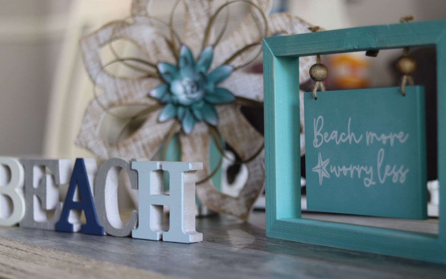 Dekorative Buchstaben mit dem Wort „BEACH“ und ein kleines Schild mit der Aufschrift „Weniger Sorgen, mehr Strand.“