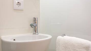 Un baño con un lavabo blanco, un perchero y un enchufe en la pared.