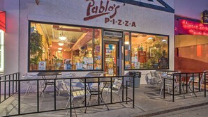 Una pizzería con mesas al aire libre y un letrero que dice "Pablo's PIZZA".