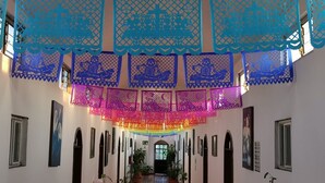 A hallway with blue and pink paper decorations, potted plants, and framed pictures on the walls.