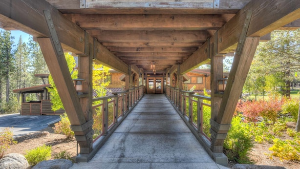 A wooden covered walkway with a sign reading "Lodge" leading to a building.