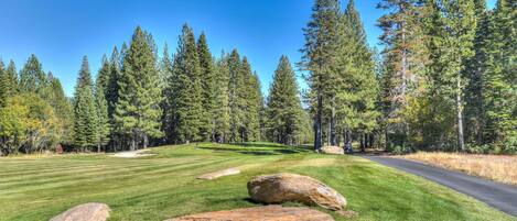 A golf course with a clear sky, green grass, and large rocks.
