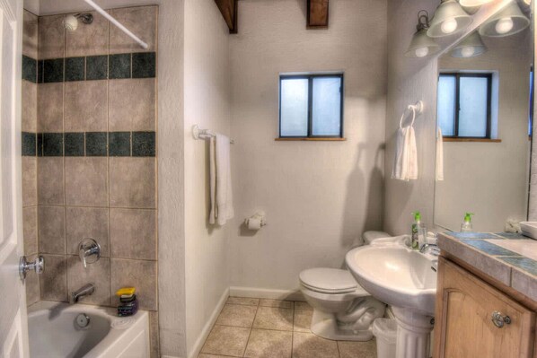 A bathroom with a bathtub, toilet, sink, and a window. - Glacier Forest Getaway HOA Access! (Truckee)