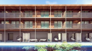 Un hotel moderno con varios balcones, piscina y mobiliario exterior.