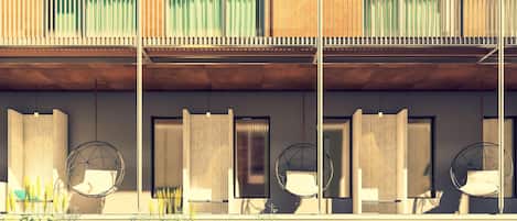 A modern building with a balcony, a pool, and hanging chairs.