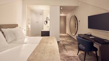 Een hotelkamer met een bed, een bureau, een stoel, een grote spiegel en een televisie.