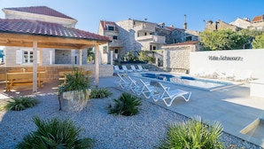 A villa with a swimming pool, outdoor seating, and a stone facade.