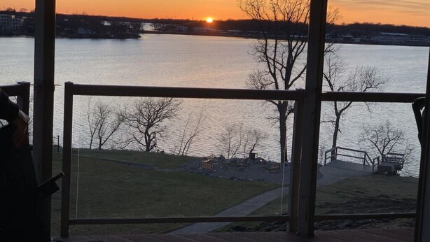 A view from a room with large windows overlooking a body of water during sunset.