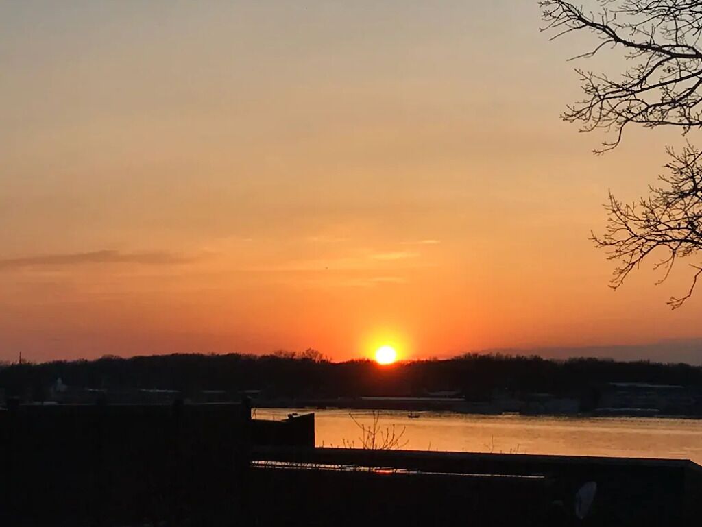 Een zonsondergang boven een wateroppervlak met gebouwen op de voorgrond.