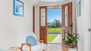 Une pièce offrant une vue sur un paysage côtier, visible à travers une porte ouverte.