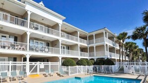 A multi-story hotel with a swimming pool, balconies, and palm trees. - The Turtles Escape (Destin)
