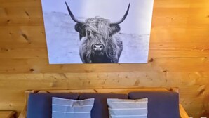 Een houten wand met een zwart-wit foto in een lijst van een stier. Daaronder een houten bank met twee kussens.
