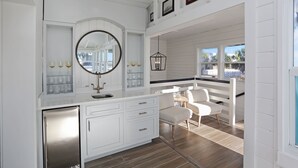 A modern kitchen with white cabinetry, a stainless steel refrigerator, and a large round mirror. - Beachview in St Joe Beach, ~ Caroline's Cottage (St. Joe Beach)
