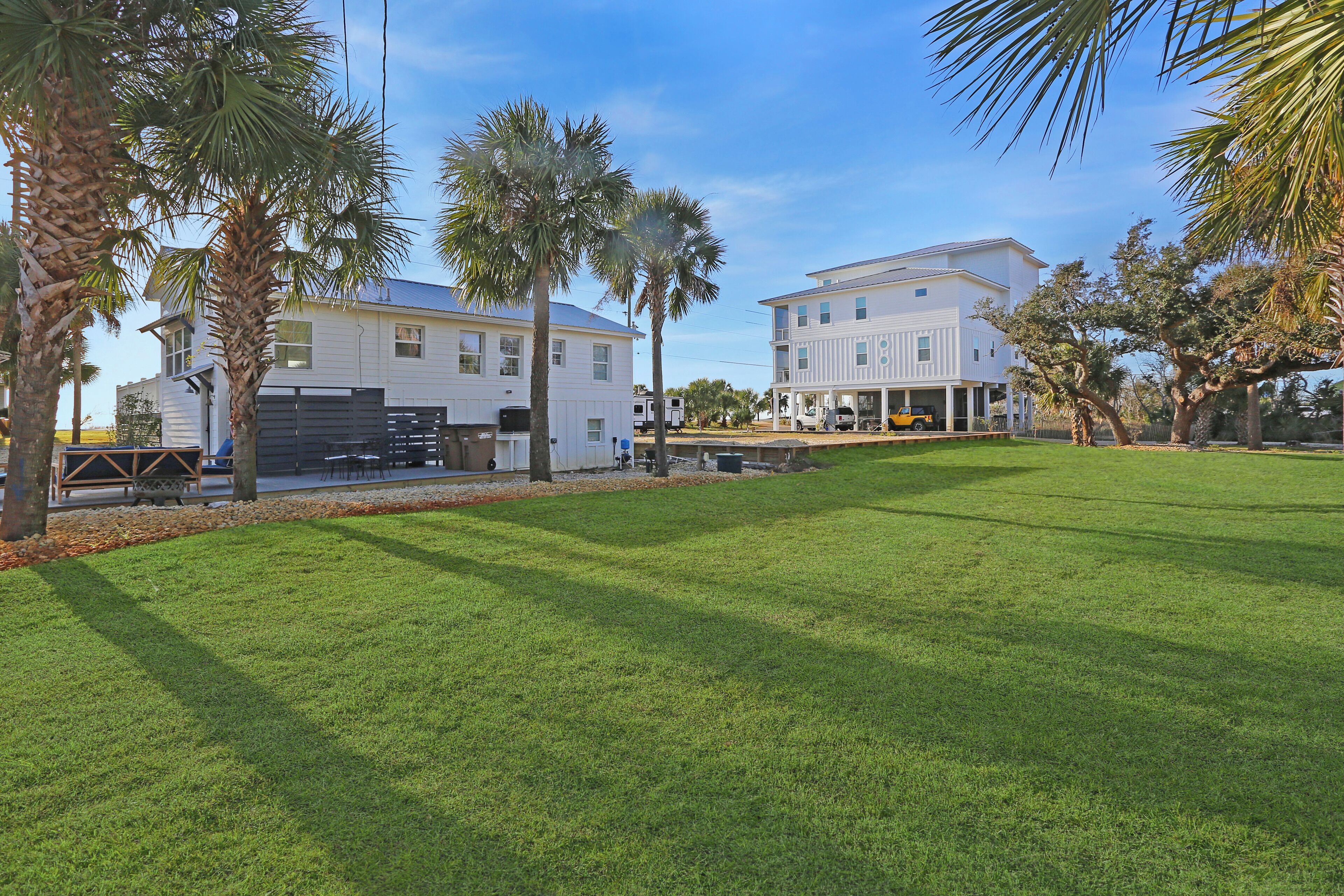 A large, white two-story building with a flat roof, surrounded by a well-maintained lawn and palm trees.