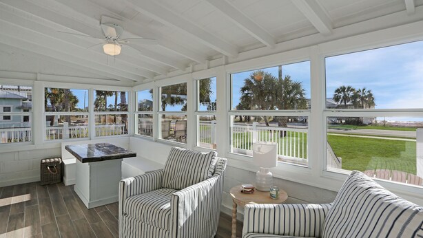 A sunroom with large windows, striped furniture, and a ceiling fan. - Beachview in St Joe Beach, ~ Caroline's Cottage (St. Joe Beach)