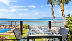 Zona de comedor junto a la piscina, con vista al océano y a las montañas.