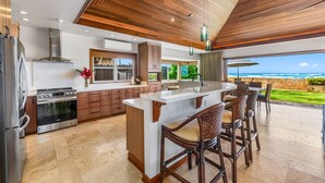 A modern kitchen with a central island, stainless steel appliances, and a view of the ocean. - Hale Makai at Diamond Head: Stunning Oceanfront Estate w/Private Pool & AC (Honolulu)