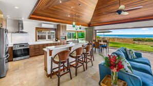 A modern kitchen with a central island, bar stools, and a view of the ocean. - Hale Makai at Diamond Head: Stunning Oceanfront Estate w/Private Pool & AC (Honolulu)