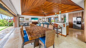 A spacious dining area with a wooden ceiling, a large wooden table, and blue cushioned chairs. - Hale Makai at Diamond Head: Stunning Oceanfront Estate w/Private Pool & AC (Honolulu)