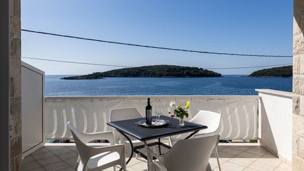 Un balcón con mesa, sillas y vista al mar.