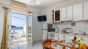 Cocina compacta con armarios blancos, microondas, refrigerador y comedor con mesa lista para el desayuno.
