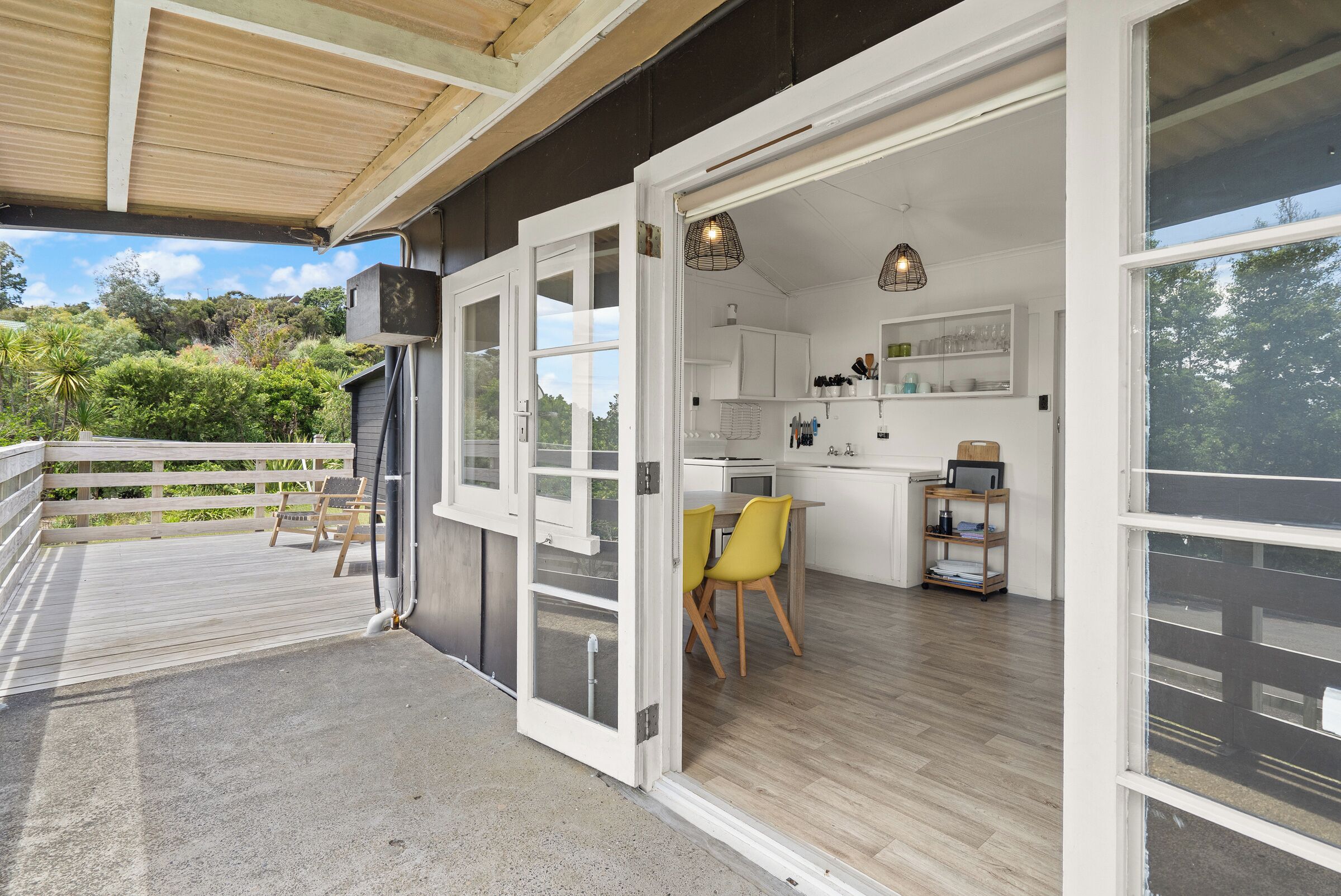 A modern kitchen with white cabinets, a dining area with yellow chairs, and a view of the outdoors.