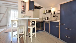 A kitchen with a white countertop, two white chairs, a stove, an oven, a dishwasher, and cabinets. - Ferienwohnung mit Meerblick, Balkon und Kamin OFC 06 - Nr. 3 Ferienwohnung mit Meerblick, Balkon und (Rerik)