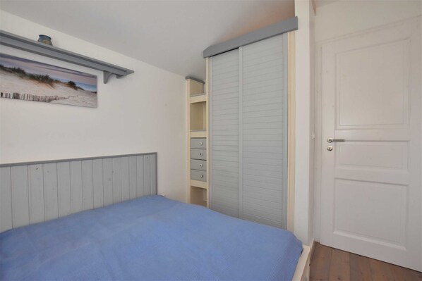 A bedroom with a bed, a wardrobe, and a door.
