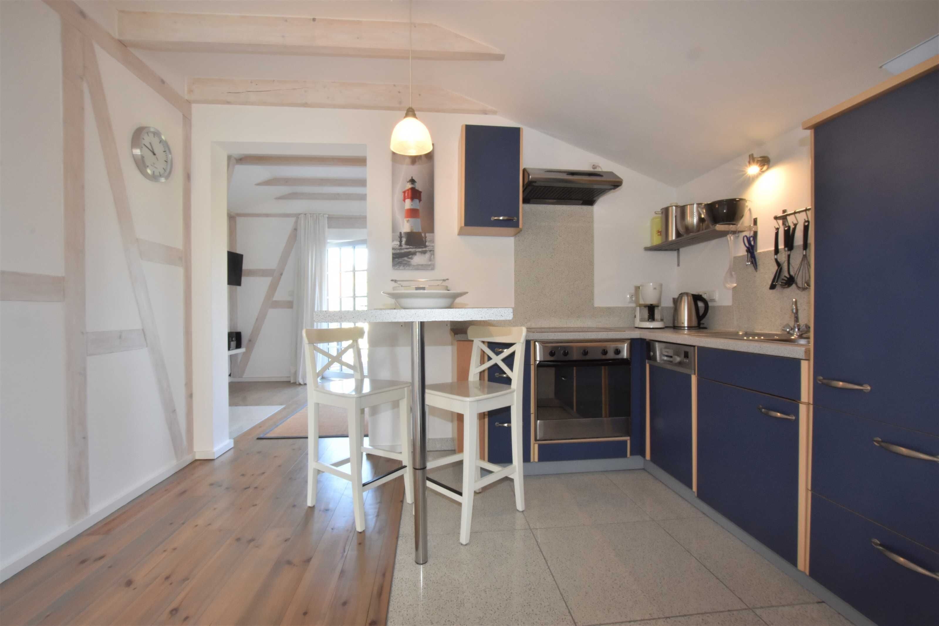 A kitchen with wooden flooring, a dining table with chairs, a stove, and cabinets.