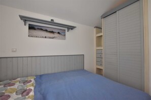 A bedroom with a bed, a dresser, a closet, and a painting on the wall.