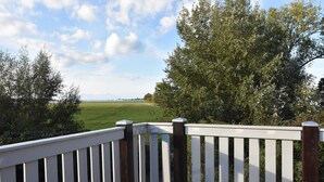 A deck with white railings and a view of a green field and trees. - Ferienwohnung mit Meerblick, Balkon und Kamin OFC 06 - Nr. 3 Ferienwohnung mit Meerblick, Balkon und (Rerik)