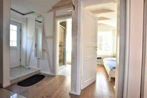A room with a bed, a door leading to another room, a small window, and a door with a mirror. - Ferienwohnung mit Meerblick, Balkon und Kamin OFC 06 - Nr. 3 Ferienwohnung mit Meerblick, Balkon und (Rerik)