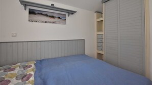 A bedroom with a bed, a dresser, a closet, and a painting on the wall. - Ferienwohnung mit Meerblick, Balkon und Kamin OFC 06 - Nr. 3 Ferienwohnung mit Meerblick, Balkon und (Rerik)