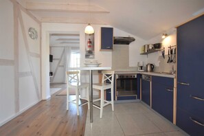 Une cuisine avec un plancher en bois, une table à manger avec des chaises, une cuisinière et des placards.