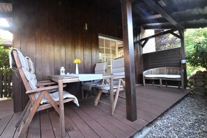 A wooden deck with a table and chairs, a bench, and a stone wall.