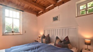 Un dormitorio con cama, dos mesitas de noche, una ventana y techo de madera.