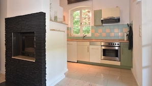 Una cocina con chimenea de piedra, ventana con vistas a la vegetación y horno empotrado.