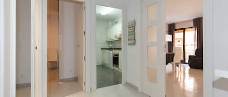 A hallway leading to a kitchen with white cabinets and a dining area with a table and chairs.