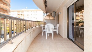 Ein Balkon mit Tisch und Stühlen, einem Geländer und Blick auf die Straße und die Häuser.
