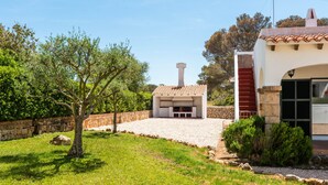 Ein Haus mit Steinmauer, Baum und einer Terrasse.