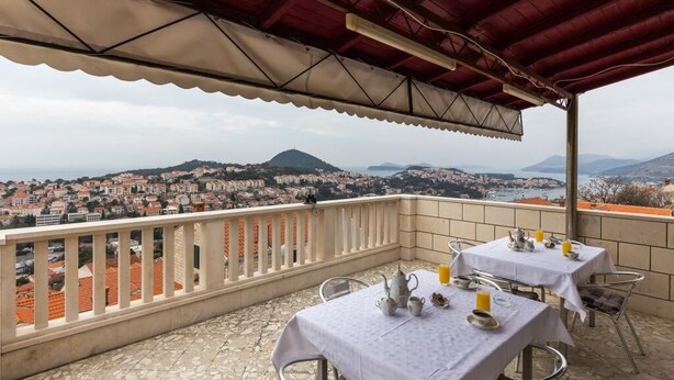 Una terraza con mesas y sillas, con vistas a un paisaje urbano de edificios y colinas.