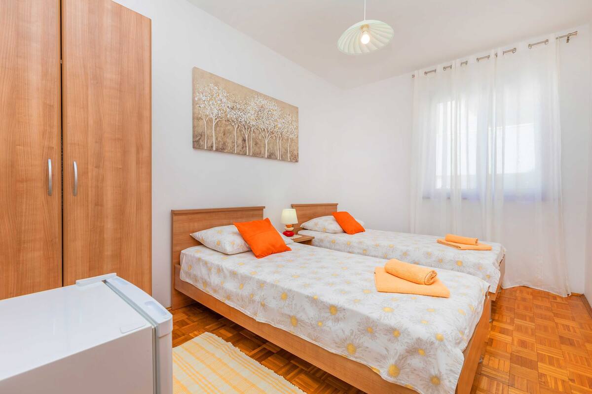 Un dormitorio con dos camas, un armario, un cuadro y una ventana con cortinas.