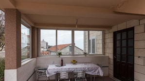 Un balcón con una mesa, sillas, una botella y un cuenco de fruta.