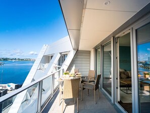 A balcony with a table and chairs, a sofa, and a glass door leading to an indoor area. - Hafenspitze App. 32, Deutschland (Wismar)
