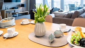 Ein modernes Hotelzimmer mit Essbereich, einer Couch, einem Fernseher und Blick auf die Stadt.