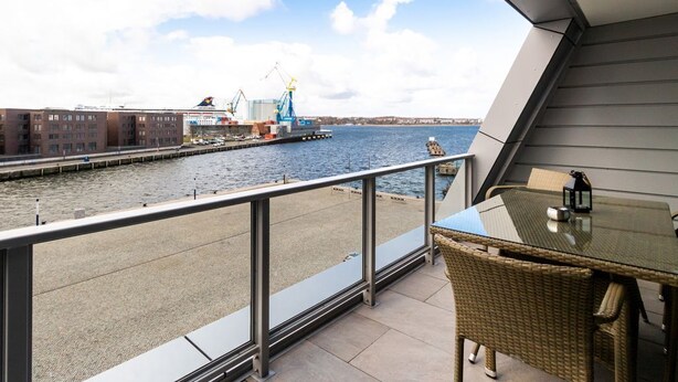 Ein Balkon mit Blick auf einen Fluss, einem Tisch und Stühlen.