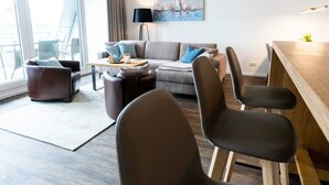 Ein modernes Wohnzimmer mit einer Couch, zwei Sesseln, einem Couchtisch und einem Essbereich.